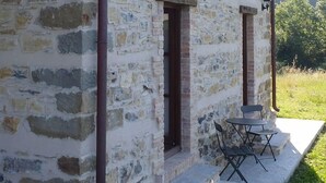 Edificio de piedra con dos ventanas y un balcón, un pequeño espacio de estar al aire libre y un farol.