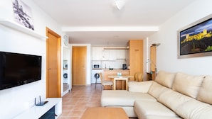 Een moderne woonkamer met een flatscreen televisie, een houten salontafel en een beige bank.