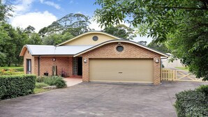 Une maison à deux étages avec un garage, une façade en briques et un toit en pente.