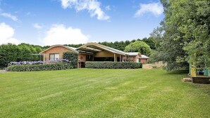 Une maison à deux étages, construite en briques, dotée d’un patio couvert et d’une pelouse bien entretenue.