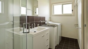 A modern bathroom with a glass shower enclosure, a double sink vanity, and a toilet.