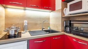A modern kitchen with red cabinets, a stainless steel sink, a coffee machine, and a microwave. - Nice apartment for 4 people with WIFI, TV and balcony (La Toussuire)