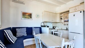 Een kleine keuken met witte kastjes, een witte koelkast en een eettafel met witte stoelen.
