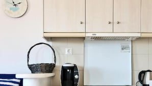 Een compacte keuken met een witte kookplaat, een klein spoelgedeelte en een kast met lades.
