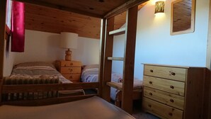 A cozy room with a wooden bed, a dresser, and a nightstand. - Pierre De Soleil -  Ski in/out, next to ski school, shops/restaurants -free wifi (Mâcot-la-Plagne)