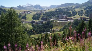 A mountainous landscape with a town featuring modern buildings and a clear sky. - Pierre De Soleil -  Ski in/out, next to ski school, shops/restaurants -free wifi (Mâcot-la-Plagne)