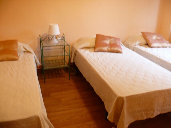 A room with two single beds, each with a pillow and a small bedside table with a lamp. - Great House with Garden between Sea and Mountain (Riudecanyes)