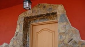 A wooden door with a stone surround, set against a red wall. - Great House with Garden between Sea and Mountain (Riudecanyes)