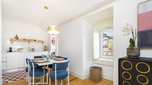 A modern kitchen with white cabinets, a wooden countertop, and a dining area with blue chairs and a white table.