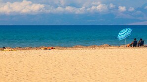 A beach with a clear sky, a sandy shore, and a blue umbrella providing shade. - Beach Villa Joanna - Luxury Villa rental in Corfu, Greece (Acharavi)