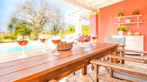 An outdoor dining area with a pool view, wooden furniture, and potted plants. - Beach Villa Joanna - Luxury Villa rental in Corfu, Greece (Acharavi)