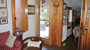 Una habitación acogedora con una puerta de madera que da a un comedor, un sofá rojo estampado y una silla de madera.