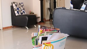 Un saló amb un sofà negre, una taula de centre amb revistes i un armari negre.