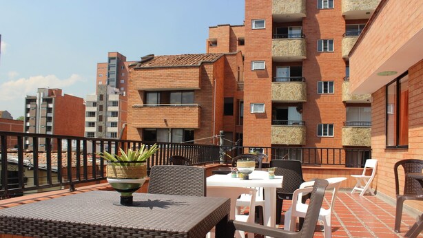 Terrassa al terrat amb seients exteriors, una planta en test i vistes als edificis veïnals.
