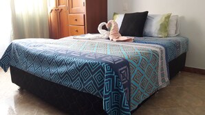 Un llit ben fet amb roba de llit estampada, un armari de fusta i un sòl de rajola.