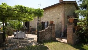 A rustic stone building with a covered patio area, a gated entrance, and a small table set outdoors.