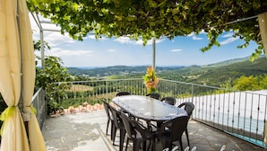 A terrace with a table and chairs, overlooking a scenic landscape. - Private House with Exclusive Swimming Pool Heated and Amazing View (Boccheggiano)
