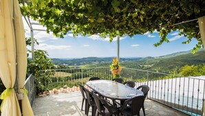 A terrace with a table and chairs, overlooking a scenic landscape.