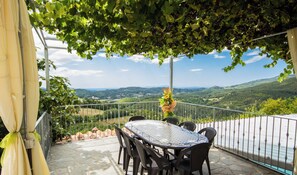 Um terraço com mesa e cadeiras, com vista para uma paisagem deslumbrante.