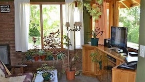 A cozy living room with a fireplace, wooden furniture, and potted plants. - Los Maitenes Bariloche (San Carlos de Bariloche)