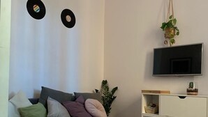 A modern living room with a grey sofa, a flat-screen TV mounted on the wall, and a small plant hanging from the ceiling. - Rome: Central apartment, in the heart of Rome (Roma)