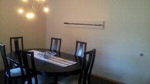 A dining room with a round table, six chairs, a chandelier, and a wall-mounted artwork. - Guesthouse Dalbaer (Hrunamannahreppur)