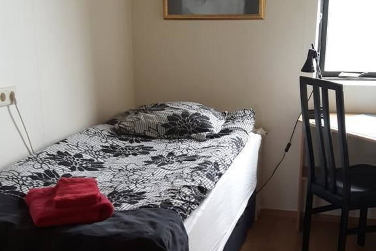 Una habitación pequeña con cama, escritorio y una silla.