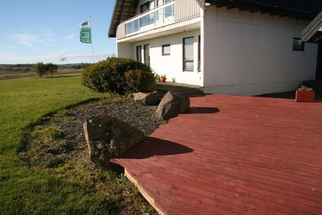A modern house with a red deck, white exterior, and a flag.