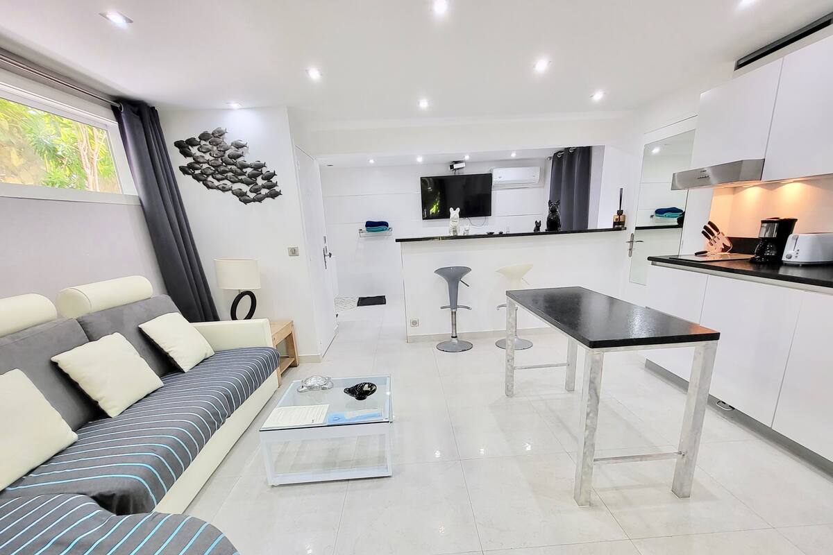 A modern living room with a sofa, coffee table, and a dining area with a table and chairs.