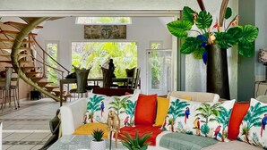 A modern living room with a glass coffee table, colorful cushions, a sofa, and a large plant. - Residence Adam & Eve (Orient Bay)
