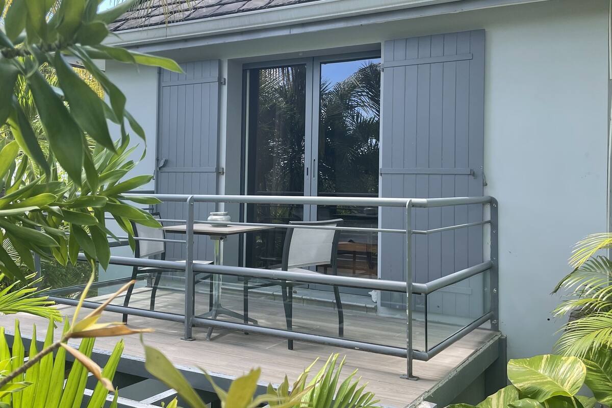 A house with a balcony, a table, and chairs.