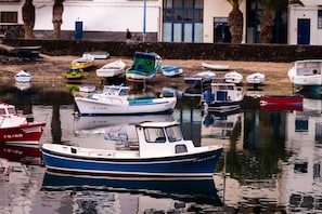 A marina with various boats docked, a calm water surface, and a building with blue doors in the background. - Rooms & Suites Loft 2E - Arrecife, Lanzarote (Arrecife)