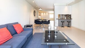 Una sala de estar moderna con un sofá, una mesa de centro y una zona comedor con sillas y una mesa.