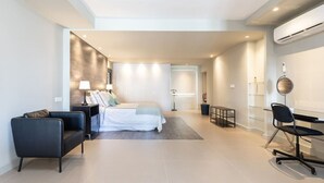Una habitación de hotel moderna con una cama, un escritorio, una silla y una mesita de noche.