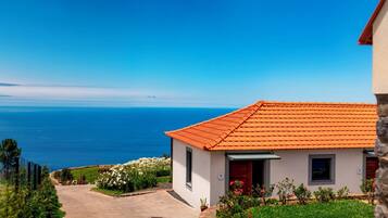 Un bâtiment situé sur la côte, doté d’un toit recouvert de tuiles, d’une allée pavée et offrant une vue sur la mer.