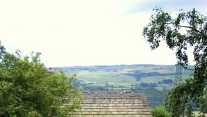 Une maison en pierre avec une allée pavée, une porte en bois et une vue sur la campagne.