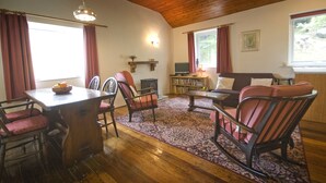 Un salon chaleureux avec un plafond en bois, une table à manger avec des chaises, un canapé et une bibliothèque.