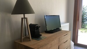 A wooden desk with a lamp, a television, and a camera.