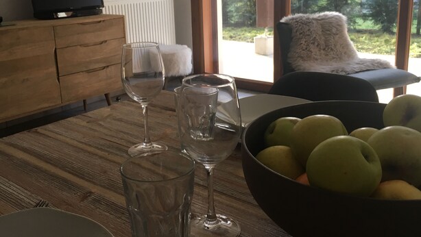 A dining table with wine glasses and a bowl of fruit.