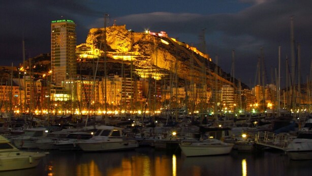 A marina with boats docked, a hotel named 'TRYP GRAN SOL HOTEL' on a cliff, and buildings with illuminated windows. - Relax & Enjoy in a property, completely reformed, high standard quality and design (Alacant)