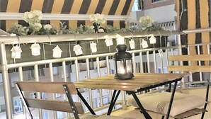 A balcony with a striped awning, a table with a lantern, and cushioned chairs. - Relax & Enjoy in a property, completely reformed, high standard quality and design (Alacant)
