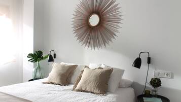 Un dormitorio con una cama, dos mesitas de noche, un espejo en la pared y una lámpara de noche.