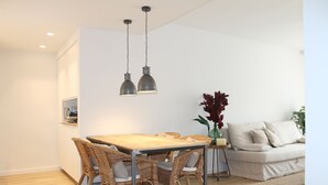 A modern living room with a dining area, featuring a wooden table, wicker chairs, a sofa, and a decorative plant. - Relax & Enjoy in a property, completely reformed, high standard quality and design (Alacant)