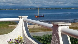 Une vue sur un lac, avec un bateau, une rambarde et une rive éloignée.