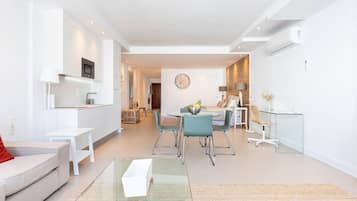 Een moderne woonkamer met een bank, een glazen salontafel en een eethoek met stoelen en een tafel.