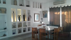 A dining area with a white table and wooden chairs, surrounded by shelves with various decorative items. - 200m from the beach, magnificent architect's apartment with rooftop and sea view (Hammamet)