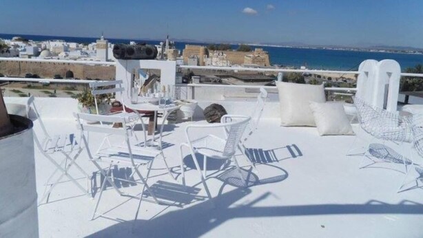 A rooftop terrace with white furniture and a view of the sea and cityscape. - 200m from the beach, magnificent architect's apartment with rooftop and sea view (Hammamet)
