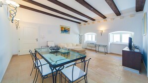 Un salón espacioso con mesa de vidrio, sofá y mueble para televisión.