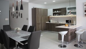 Una cucina moderna con isola centrale, mobili in legno scuro e piano di lavoro bianco.