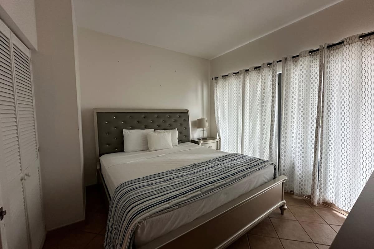 Ein Schlafzimmer mit einem Bett, einem Nachttisch und einem Fenster mit Vorhängen.